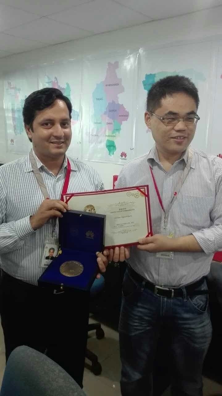 Anower Sadath Kabir and a Huawei executive holding a medal and a certificate of commendation