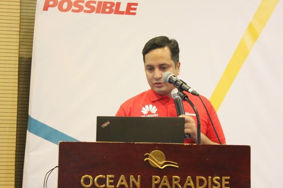 Anower Sadath Kabir in a Huawei shirt presenting at a lectern at Ocean Paradise